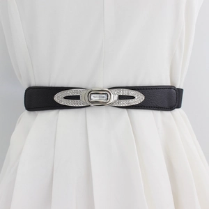 Cintura elastica nera da donna con fibbia di strass su un vestito bianco