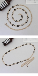 Detail view of a gold waist chain featuring black diamond-shaped enamel inserts and lobster clasp
