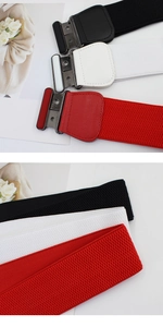 Close-up of three elastic wide belts in black, white, and red with metal buckles