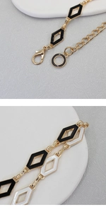 Detailed macro view of the gold chain belt featuring black and white enamel diamond links