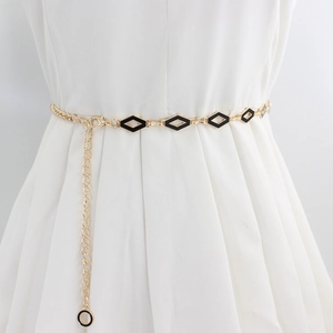 Elegant gold metal waist chain with black diamond enamel charms on a white pleated dress