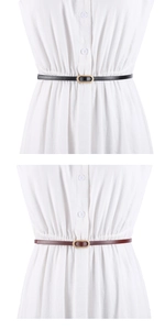 Detail view of thin leather belt with oval gold buckle on a white dress for styling