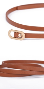 Detail view of champagne gold oval buckle and fine leather texture of the brown slim belt