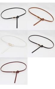 Detail view of five assorted slim leather belts with golden oval buckles for women