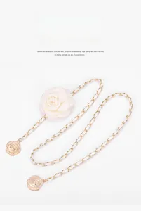 Detail of camellia waist chain with gold metal links and white woven leather texture