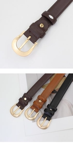 Détails de boucles dorées en demi-cercle sur ceintures en cuir noir et marron