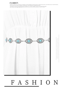Detail of silver chain belt with turquoise oval stones on a white dress waist