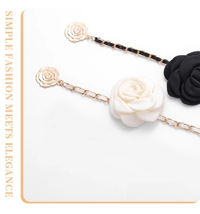 Macro detail of camellia waist chains in black and white with gold metal woven leather