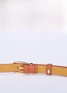 Vue détaillée de la ceinture en cuir marron avec boucle dorée et coutures précises