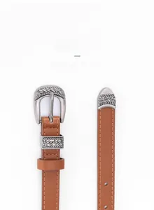 Detail of vintage silver carved buckle and tip on a caramel brown slim leather belt