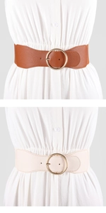 Detail of wide leather waist belts in brown and beige with large round golden metal buckles
