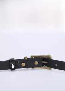 Detail of vintage bronze buckle on slim black leather belt with minimalist design
