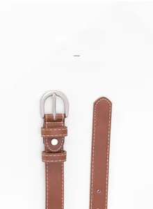 Détail de la ceinture en cuir marron avec boucle en D argentée et coutures blanches