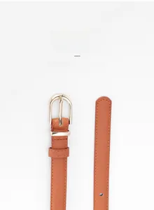 Détail d'une fine ceinture en cuir marron avec boucle en D dorée et coutures précises