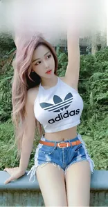 Détail d'une ceinture fine en cuir orange avec boucle dorée sur un short en jean
