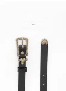 Detail of vintage carved bronze alloy buckle and black leather belt with heart pattern