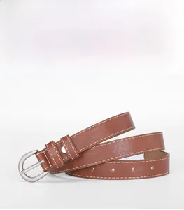 Détail d'une ceinture en cuir marron avec boucle argentée et 12 œillets pré-percés