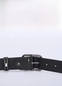 Detail of a minimalist black leather belt with gunmetal buckle and stitching on a gray background