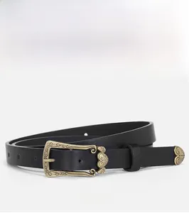 Detail of a thin black leather belt with vintage floral engraved bronze buckle and tip