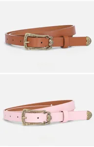 Detail of vintage carved bronze heart buckles on pink and brown thin leather belts