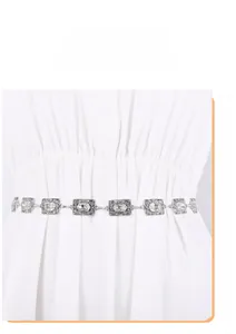 Detailed view of vintage silver metal waist chain with rhinestones on white dress