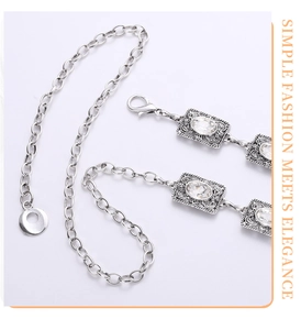 Macro detail of rhinestone-inlaid metal waist chain with elegant silver baroque patterns