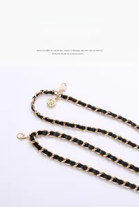 Detail of gold metal chain woven with black leather and camellia flower charm