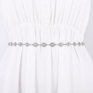 Elegant silver metal waist chain with rhinestone flowers on a white dress