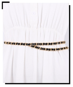 Close-up of golden metal chain belt woven with black leather on white sweater dress