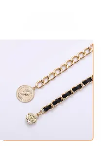 Detail of golden metal chain belt featuring relief coin charms and rose flower pendants