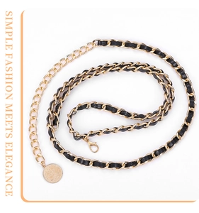 Detail of gold metal chain belt with black leather weave and round coin pendant charm