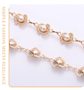 Macro detail of golden waist chain with delicate plum blossom pearls and shell charms