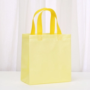 Detail of light yellow non-woven tote bag with reinforced stitching and textured finish