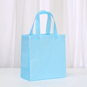 Detail of light blue non-woven gift bag with reinforced stitching and textured surface