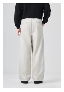 Detail view of light beige wide-leg trousers featuring a premium drape and back welt pockets