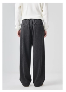 Rear view of loose-fit dark grey trousers showing drape and pocket details