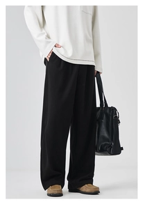 Detail view of men's wide-leg black trousers with a soft drape and straight-cut design