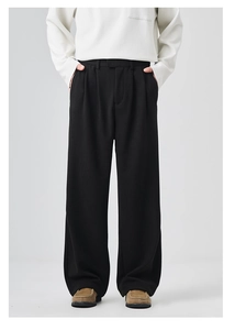 Detailed texture of thick black draped wool trousers for men with single pleat design