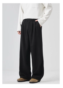 Detail view of men's black wide-leg trousers featuring draped twill fabric and single pleats