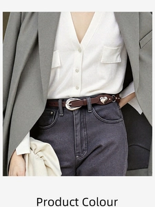 Détail d'une ceinture marron foncé avec clous en cœur et boucle argentée sur un jean