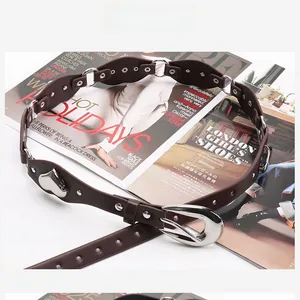 Détail de la ceinture en similicuir marron avec breloque cœur et rivets sur un magazine