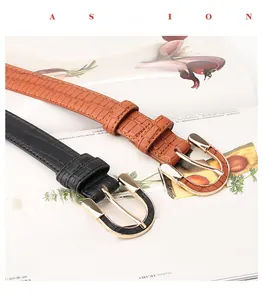 Detail view of crocodile textured leather belts with golden horseshoe buckles in black and brown