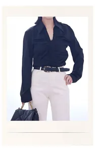 Detail of a thin black leather belt with a golden U-shaped buckle on white jeans