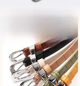 Detail of slim leather belts with crocodile texture in multiple colors and silver buckles