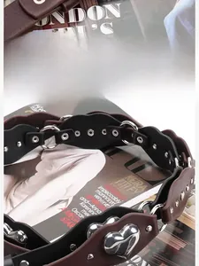 Détail de rivets argentés en forme de cœur et bords ondulés sur une ceinture punk