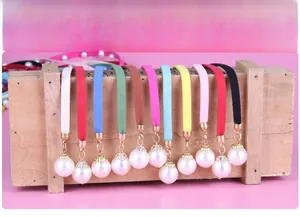 Detail of colorful velvet waist ropes with imitation pearl pendants in eleven vibrant colors