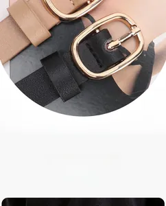Detail of elegant black and beige leather belts with polished gold oval metal buckles