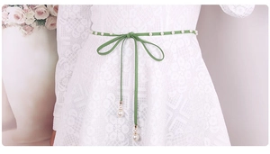 Detail of green velvet waist rope with faux pearls on white lace dress accessory
