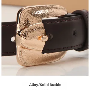 Macro view of gold alloy hammered texture buckle on dark brown fashion belt for women