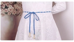 Blue velvet waist rope with pearls and pendant detail on white lace dress